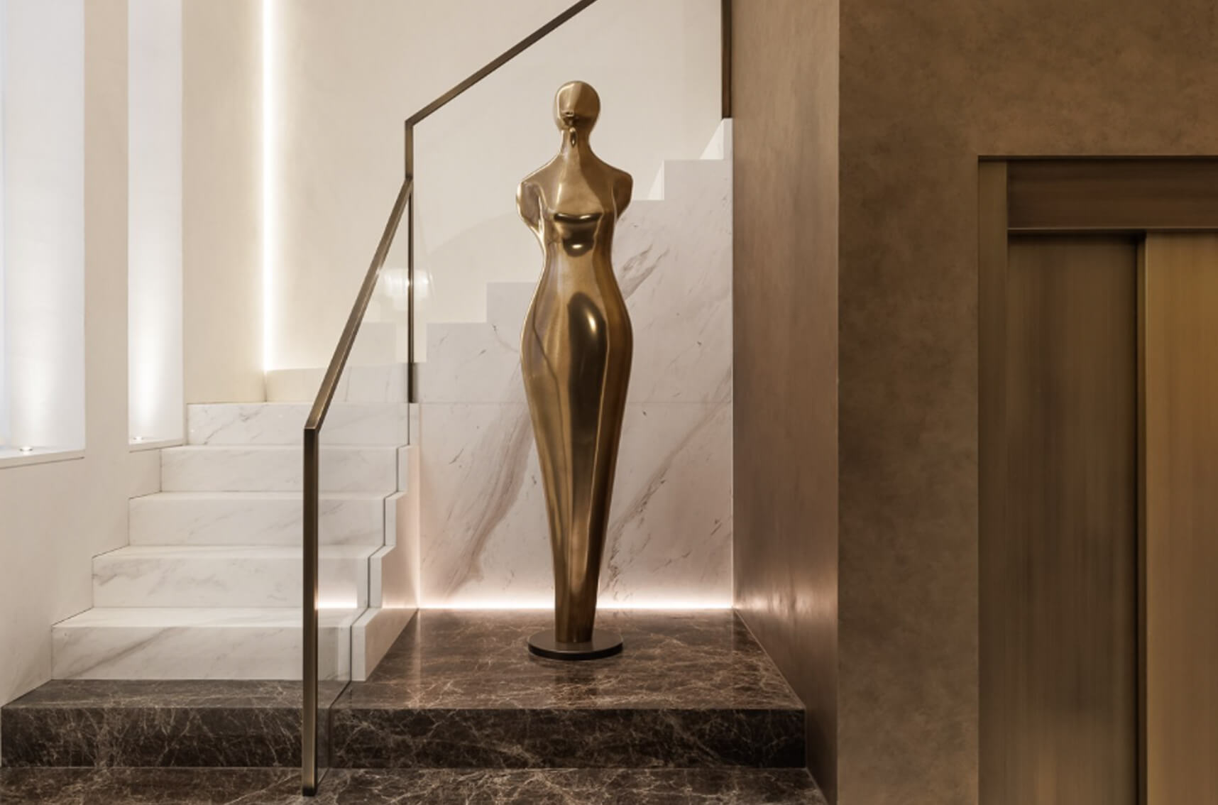 Contemporary bronze-toned sculptural artwork positioned within a luxury interior entrance, creating a striking focal point and enhancing the architectural design.
