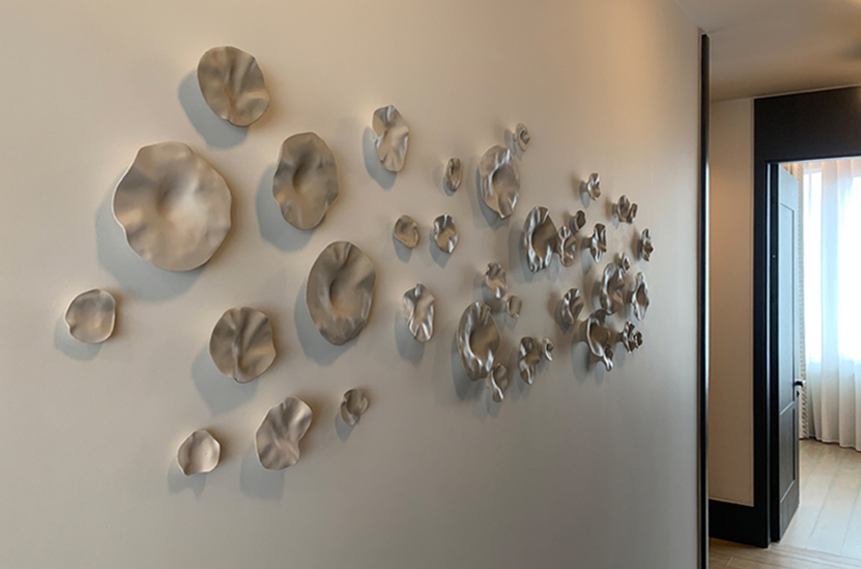 Modern sculptural wall installation featuring textured metallic forms, demonstrating the growing popularity of relief and three-dimensional artwork in contemporary interior design.